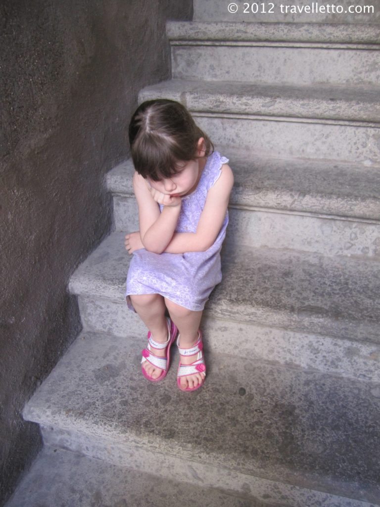 5 year old girl sitting on step looking annoyed